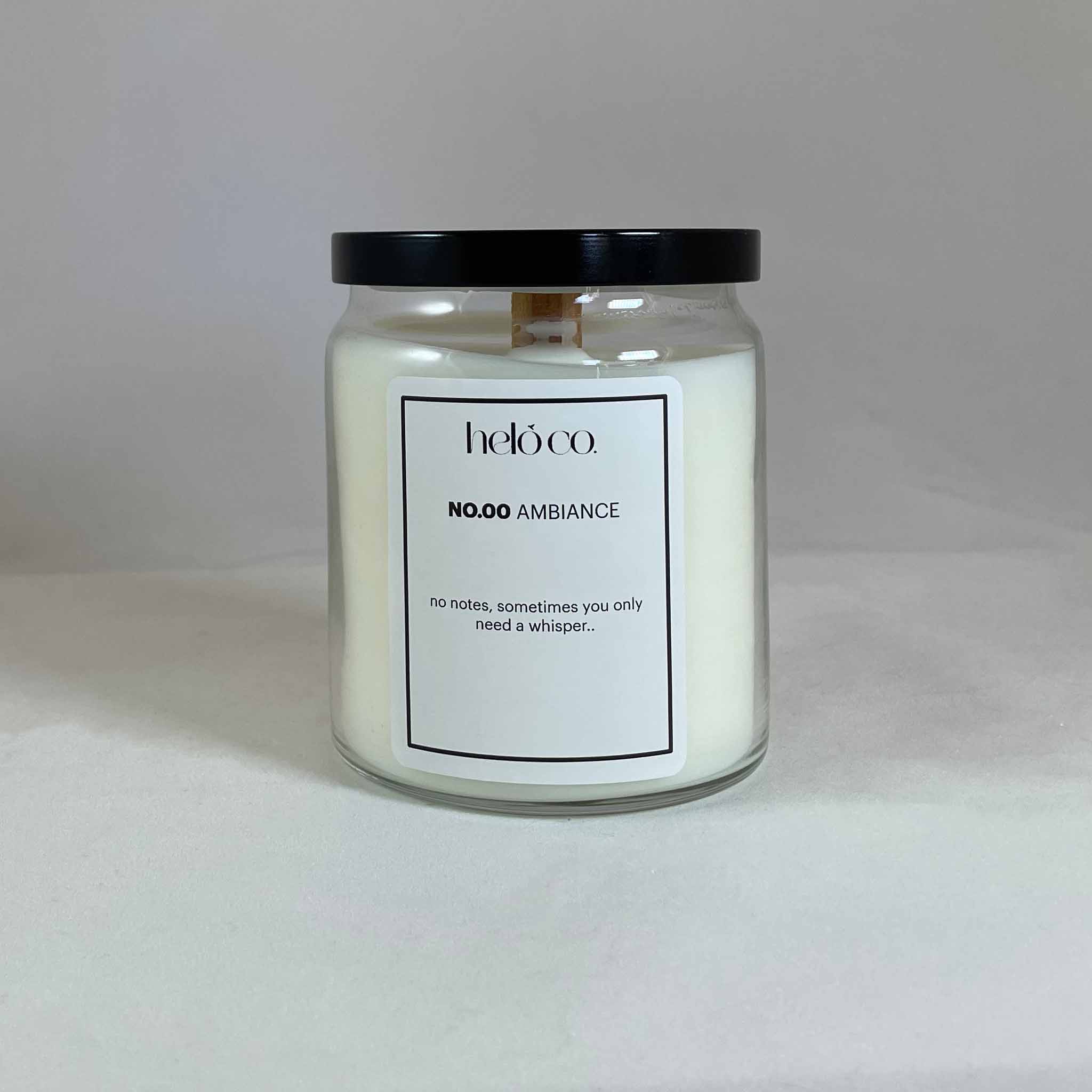 glass apothecary jar candle with a black metal lid and a white label with black text.