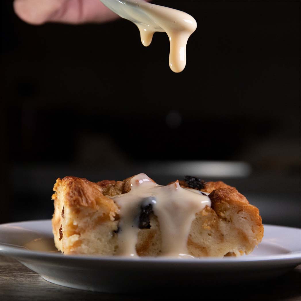 delicious bread pudding being topped with thick, sticky cream