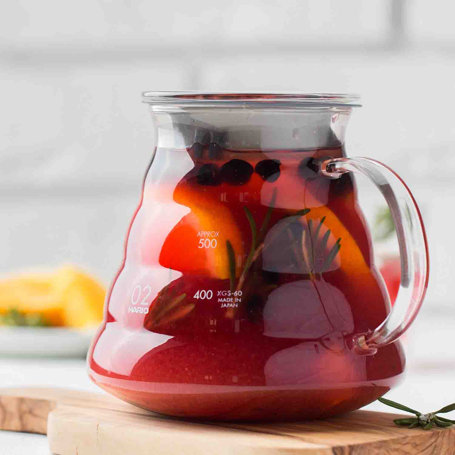 clear glass carafe of red tea with orange slices and herbs